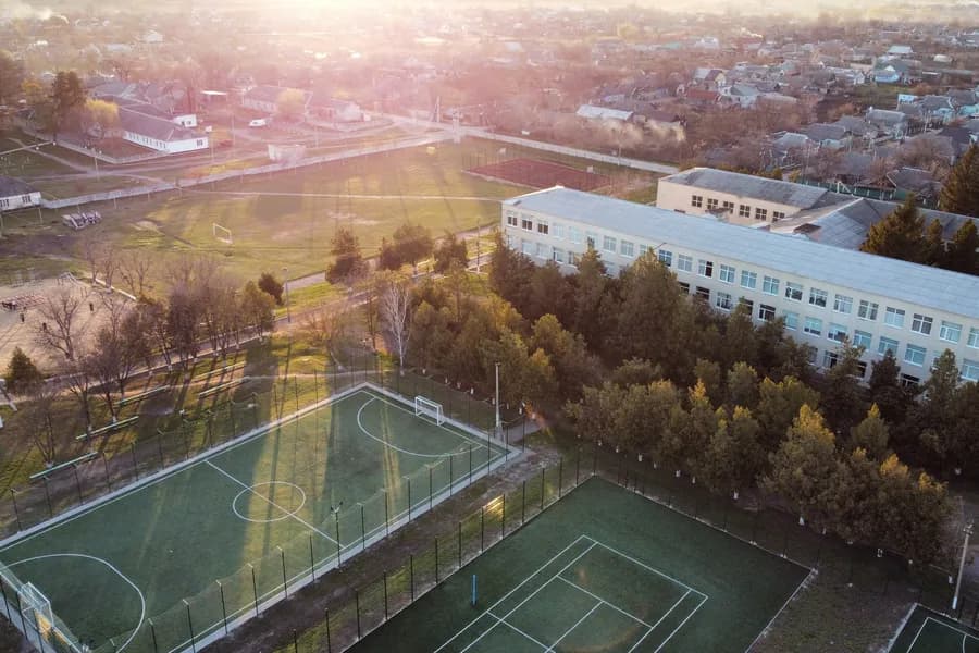 Vista aérea de uma escola com quadras esportivas ao entardecer